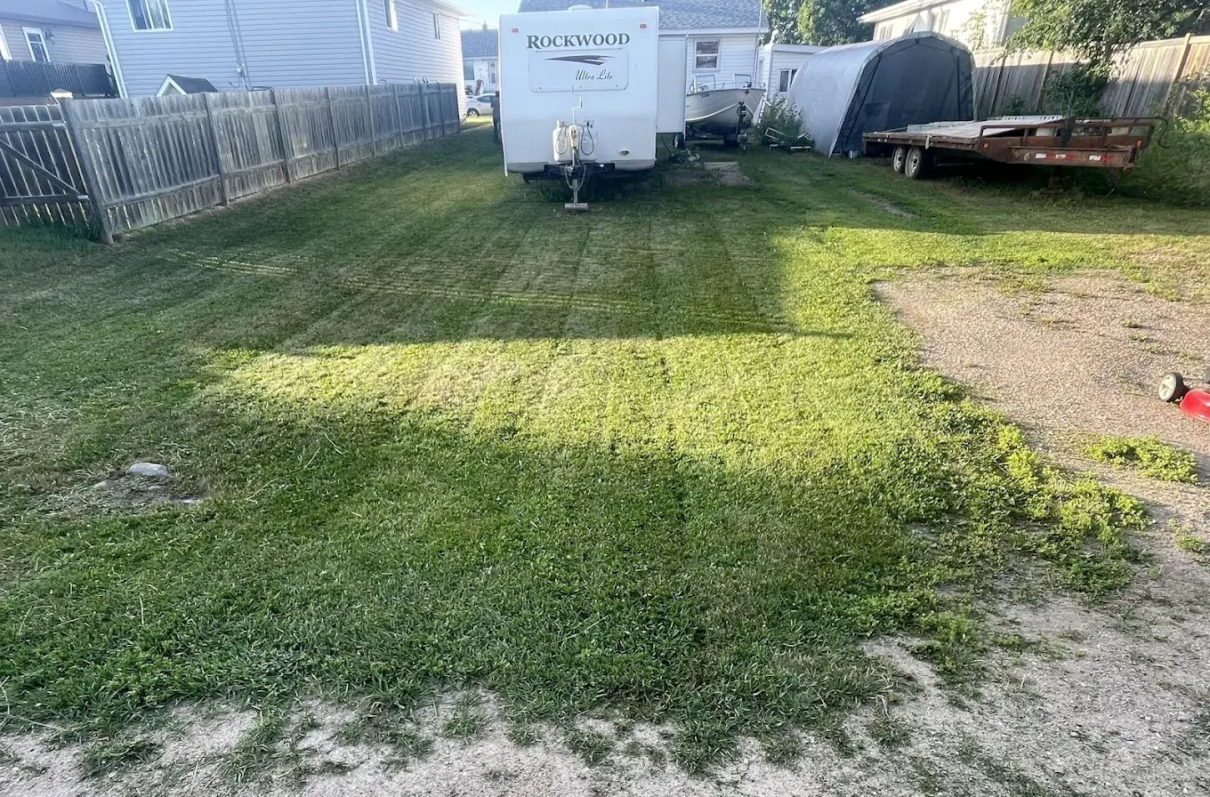 Large backyard mowed around an RV and trailer